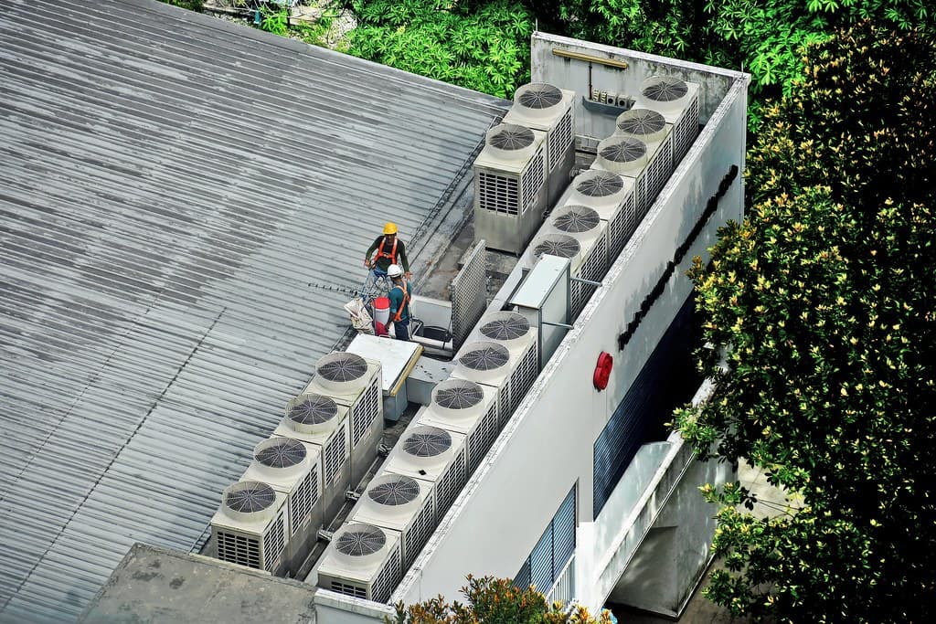 Technician beside rows of air conditioning condensers on a rooftop